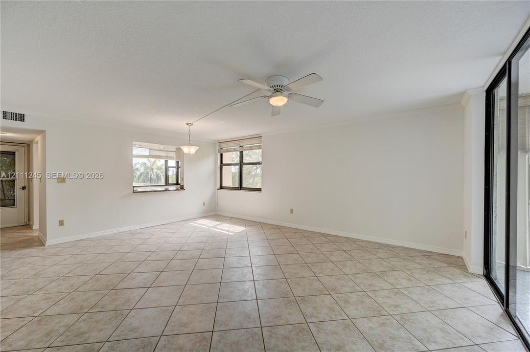 Open floor plan featuring tile flooring, multi-pane windows, a ceiling fan with integrated light, and sliding glass doors