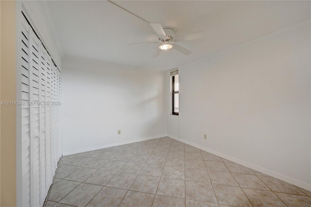 Interior space featuring diagonal tile flooring, white louvered closet doors, and a ceiling fan with integrated lighting
