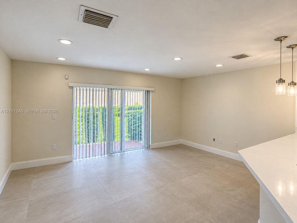 Large-format tile flooring, recessed ceiling lighting, sliding glass doors, and dual pendant light fixtures