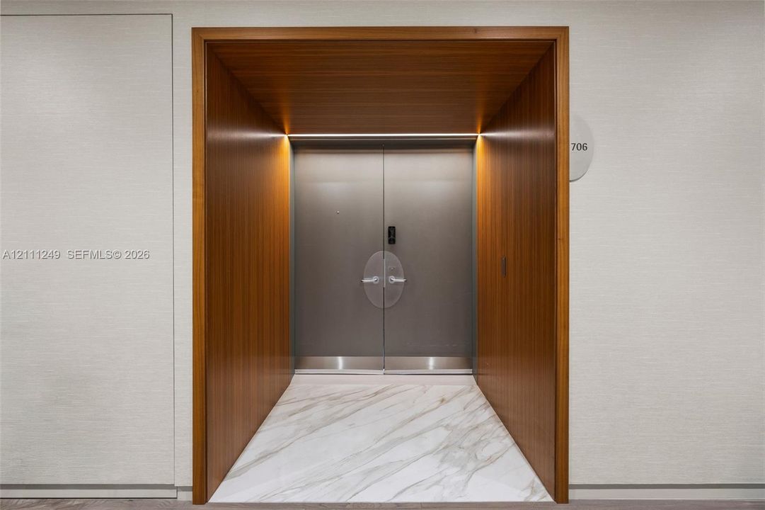 Stone tile flooring featuring geometric inlay, recessed lighting, and a white interior door with matte black hardware