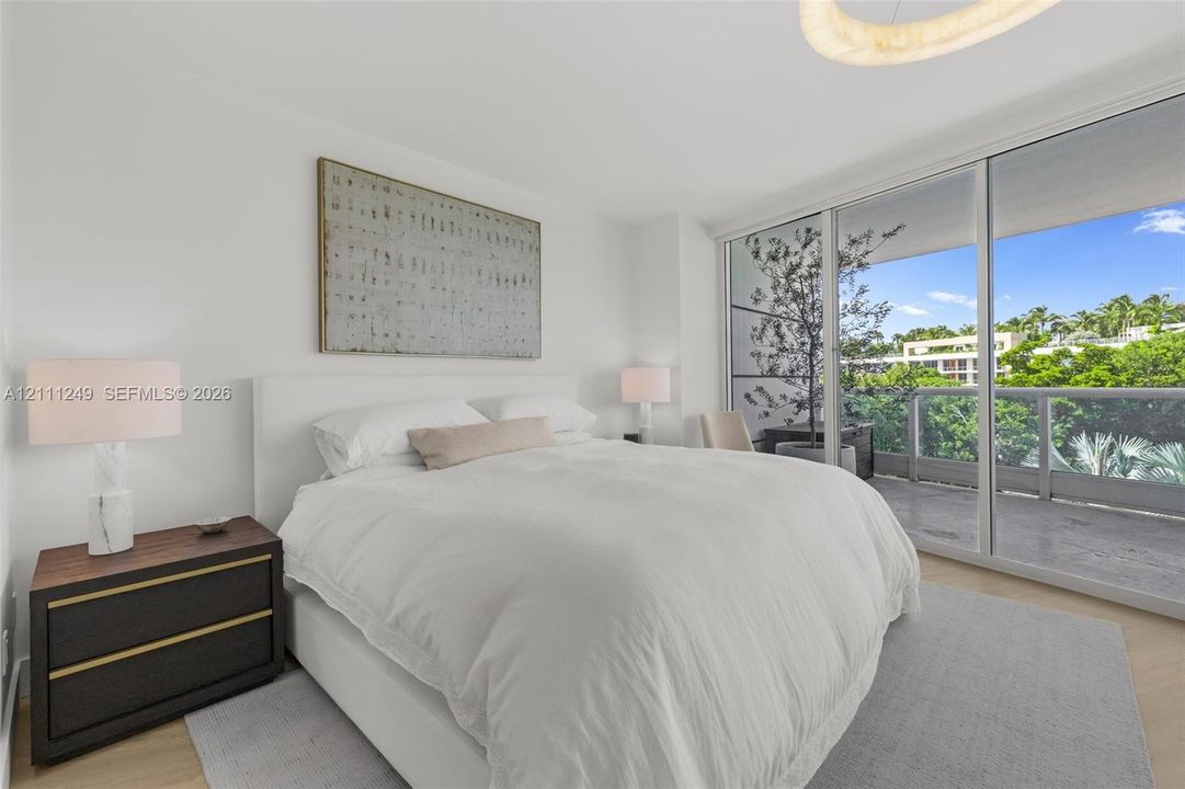 Floor-to-ceiling sliding glass doors, neutral interior walls, wood-finish flooring, and a glass-paneled balcony