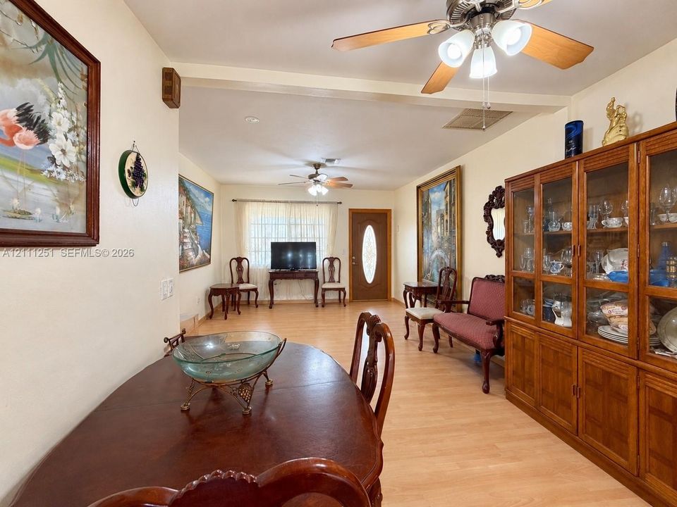 Interior space featuring light-toned wood-finish flooring, dual ceiling fans with integrated light fixtures, and a wood-encased glass-front built-in cabinet