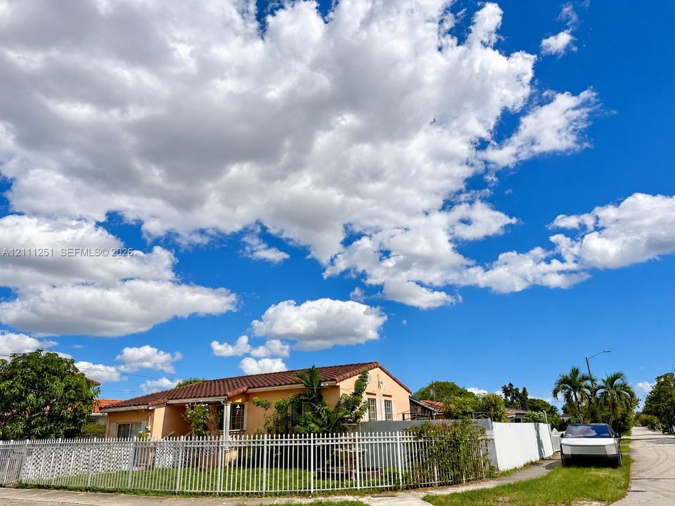 Single-story residence featuring a terracotta-tiled roof, light-toned exterior finish, and a white metal perimeter fence