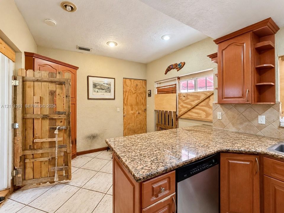 Kitchen featuring stone-finish countertops, ceramic tile flooring, built-in wooden cabinetry, recessed lighting, and a stainless steel dishwasher