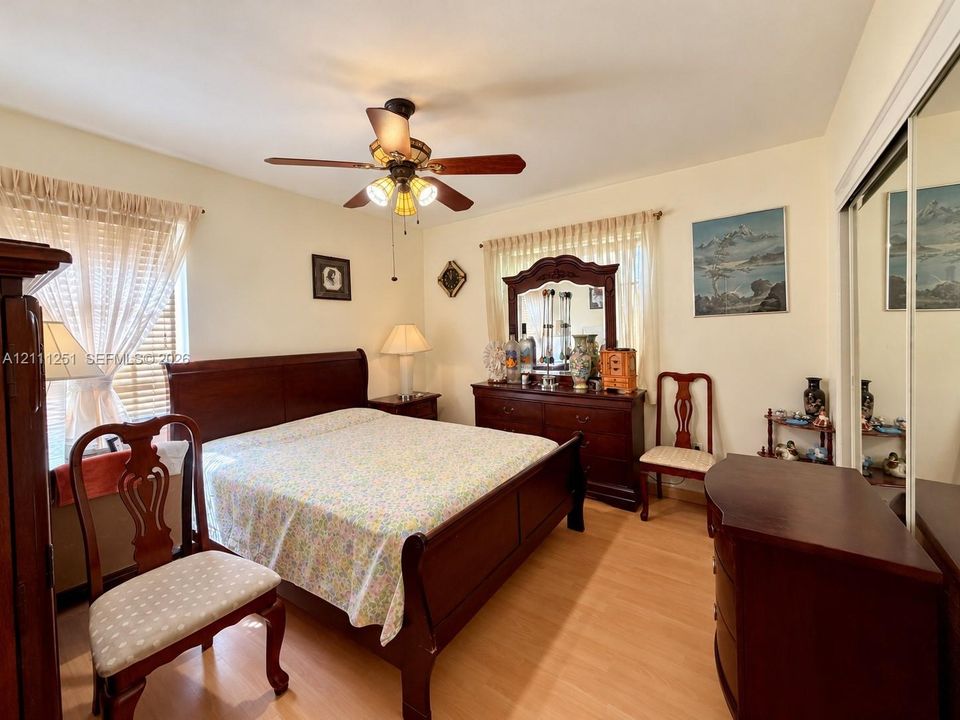 Wood-finish flooring, ceiling fan with integrated lighting, and mirrored sliding closet doors