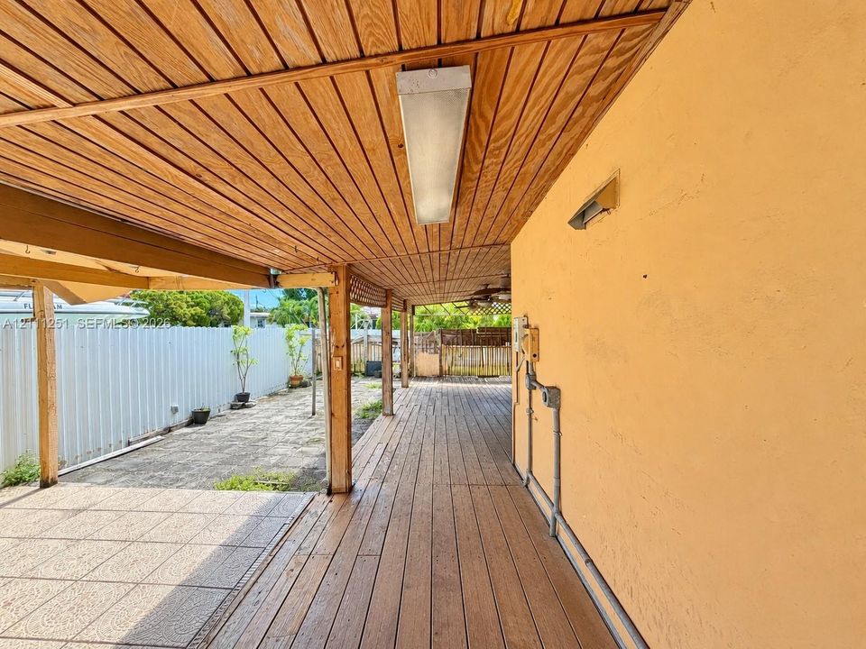 Covered patio featuring wood-paneled ceiling, wood-plank flooring, and concrete pavers