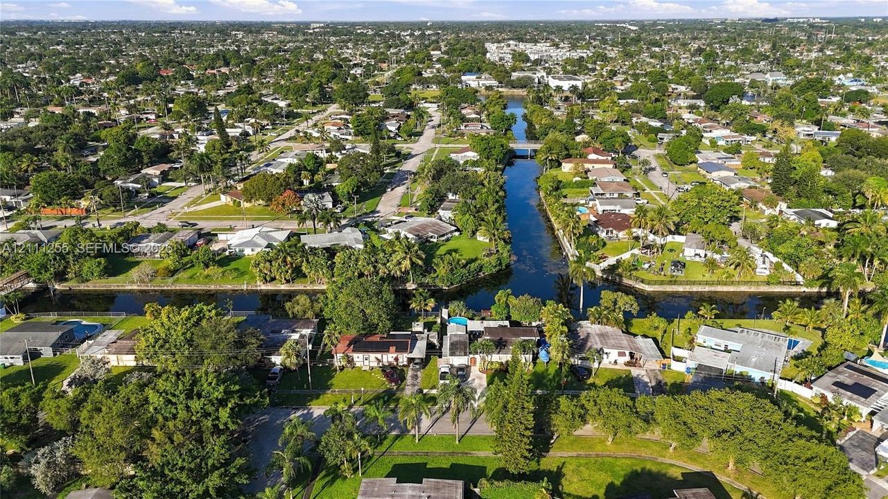 Aerial perspective of a residential neighborhood featuring waterfront access, intersecting canals, mature landscaping, and established tree canopy