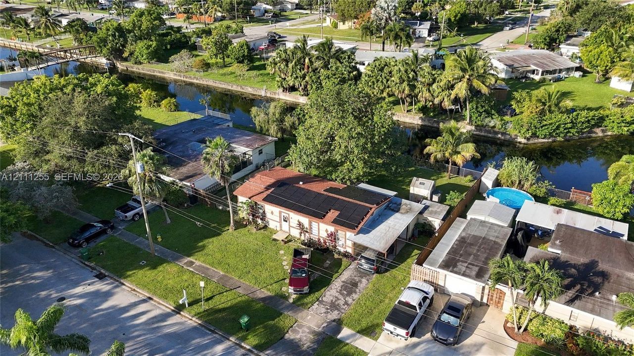 Single-story residence featuring a shingled roof, roof-mounted solar panels, an attached carport, and a direct water frontage location