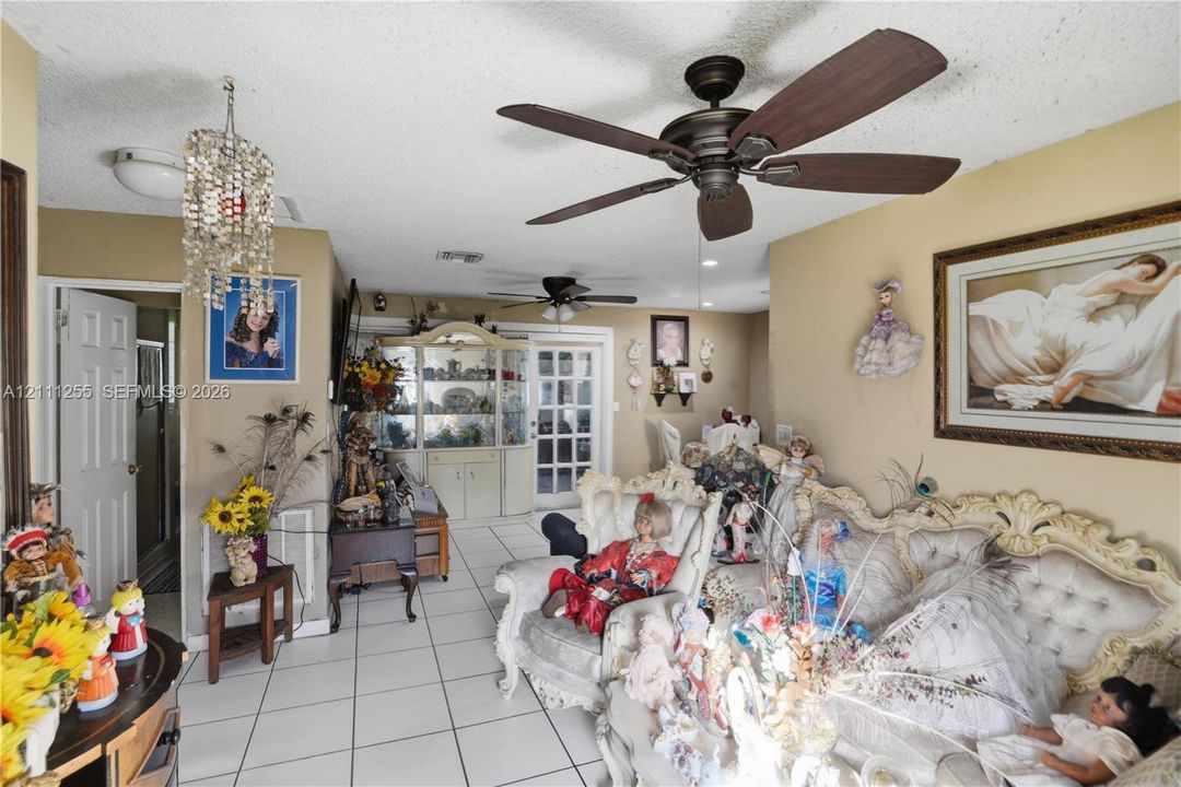 Tile flooring, built-in display cabinetry, dual ceiling fans, and a multi-pane glass entry door