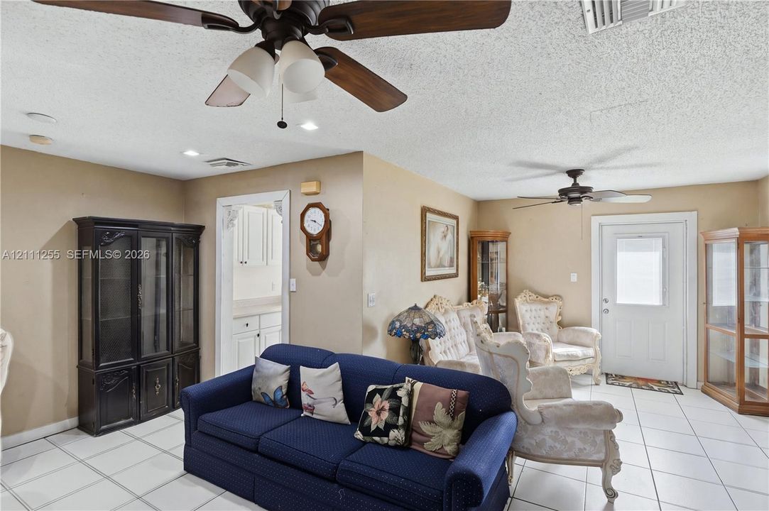 Interior space featuring neutral wall paint, white tile flooring, dual ceiling fans, and a white exterior entry door