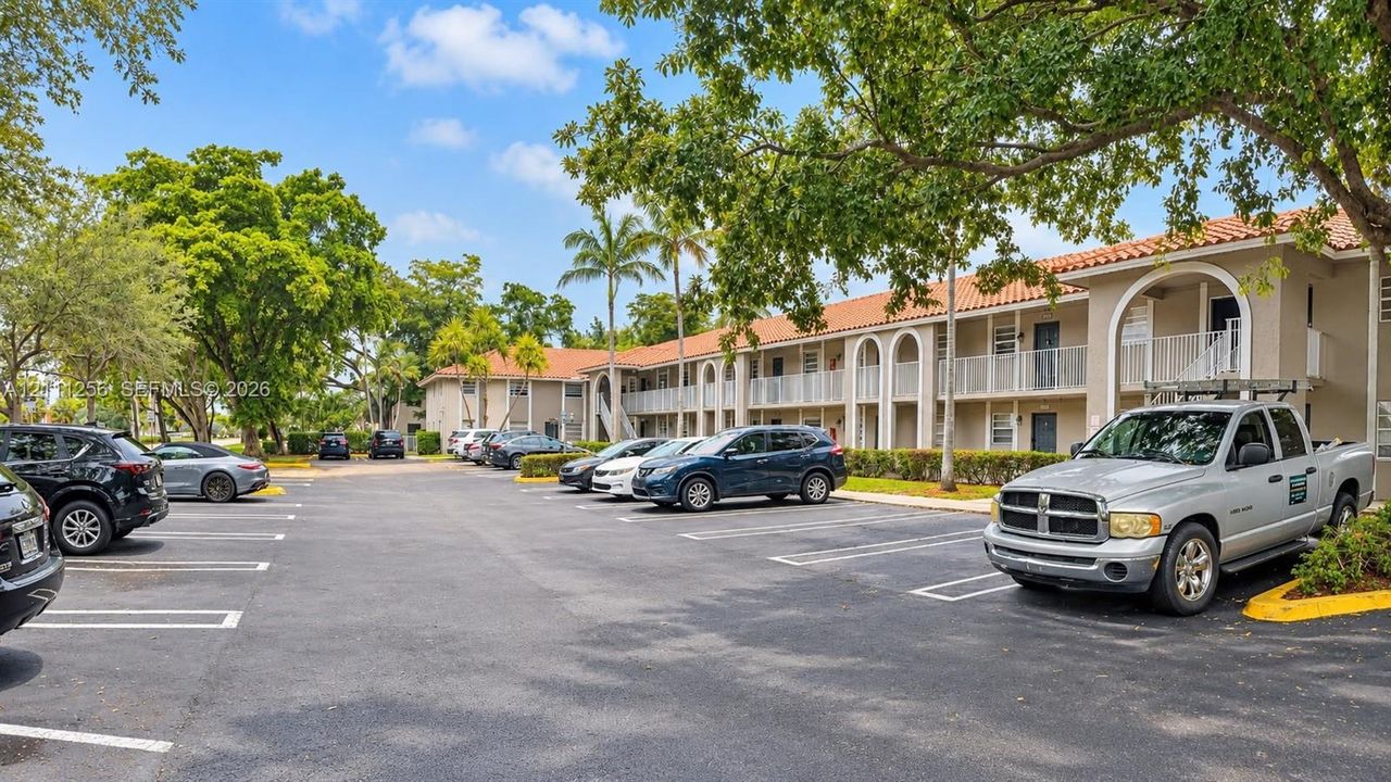 Two-story building featuring stucco exterior, clay tile roof, arched architectural details, and paved surface parking
