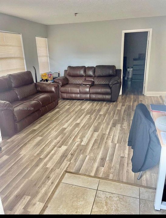 Neutral interior featuring wood-finish flooring, light gray wall paint, and horizontal window blinds