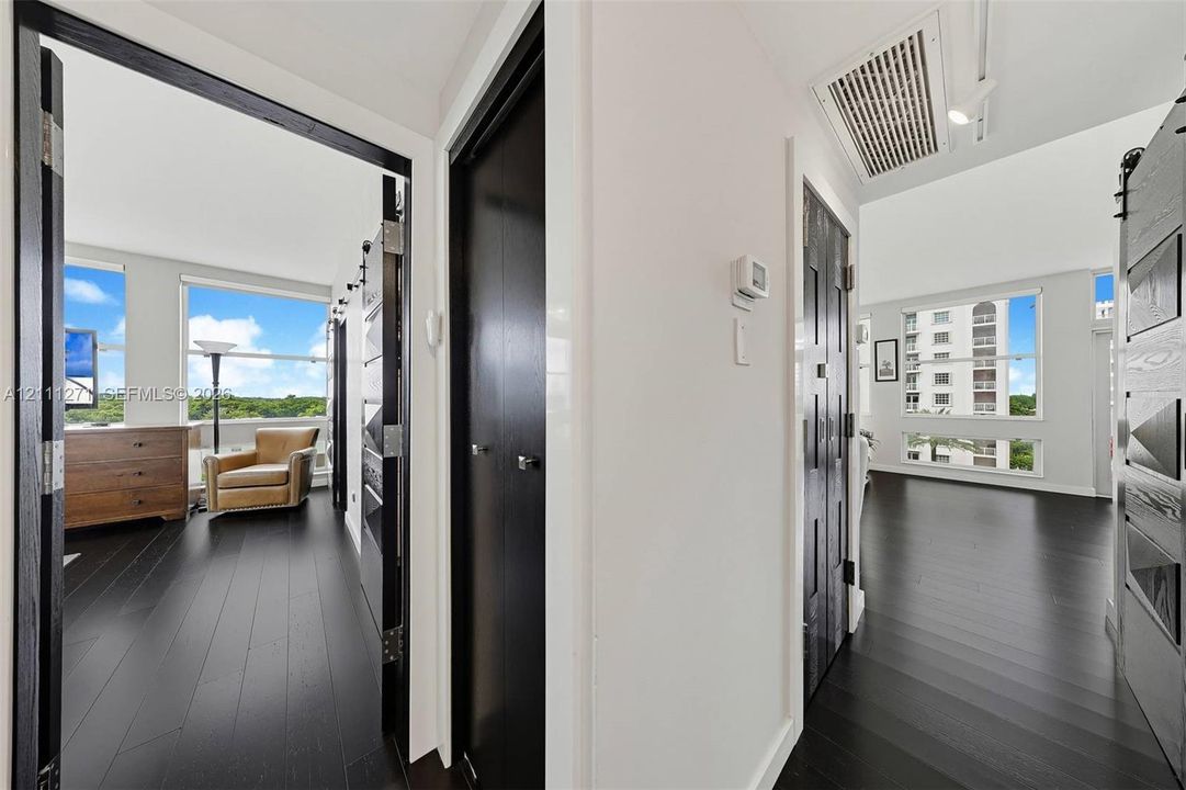 Dark-toned wood-finish flooring, high-contrast door frames, sliding barn-style doors with metallic hardware, and expansive windows
