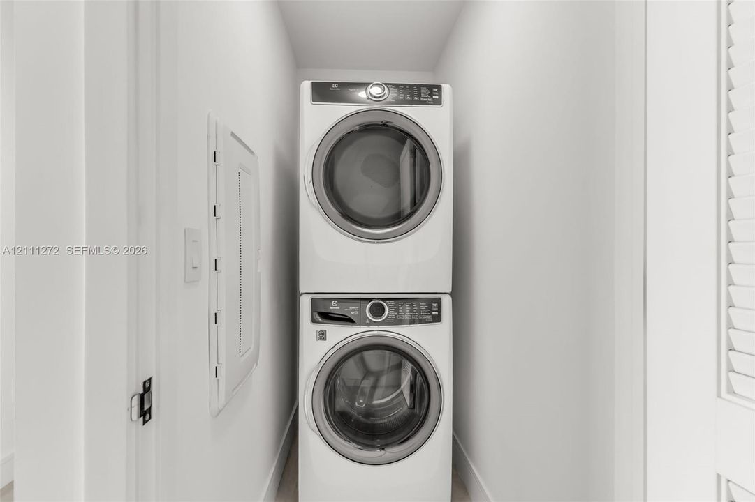 Stacked white front-load washer and dryer unit with digital control panels