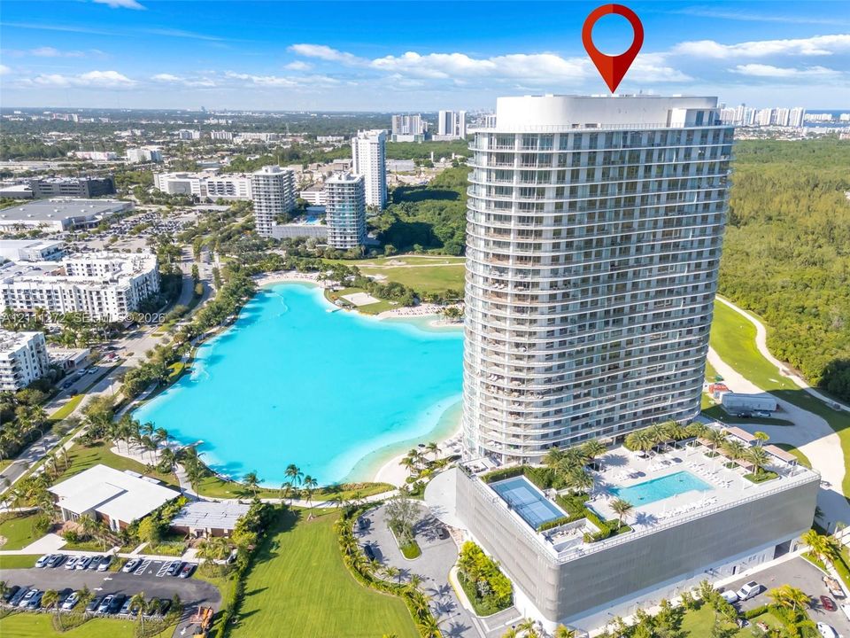 High-rise residential tower featuring a multi-story glass facade, a private elevated outdoor swimming pool, and dedicated hardscaped parking structures