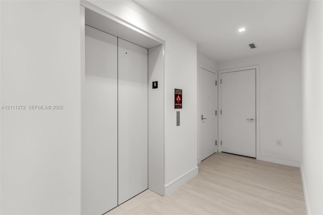 Elevator access with flat-panel doors, light-toned wood-finish flooring, and recessed LED ceiling lighting