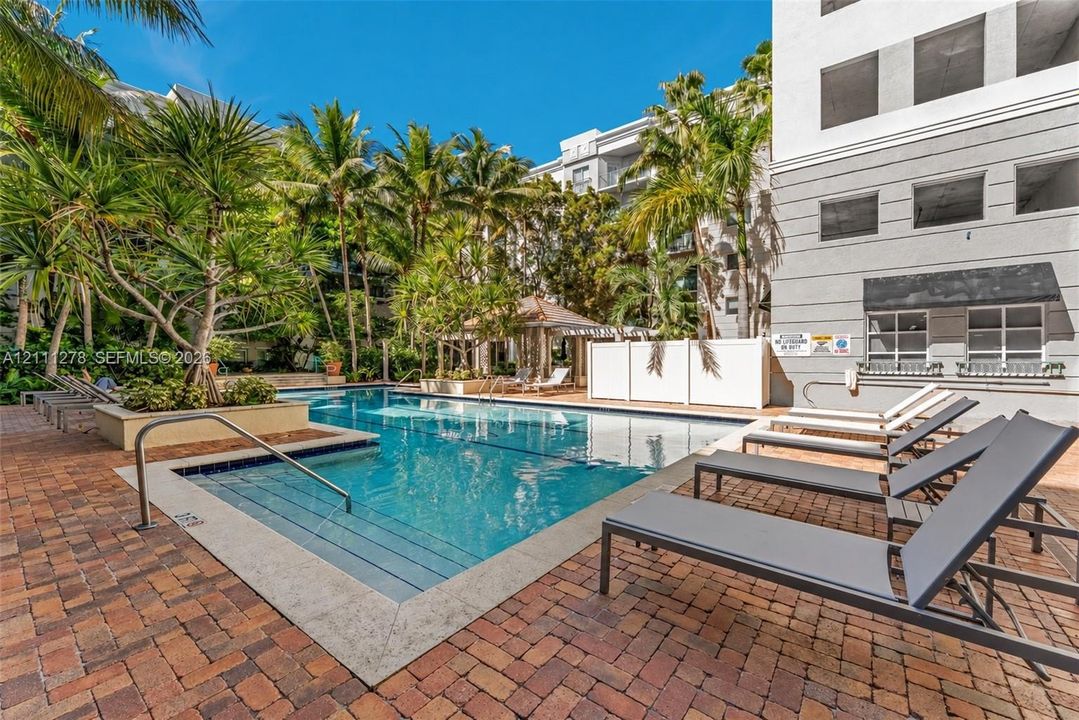 Swimming pool with tiered entry steps, stone paver decking, built-in planters, and a covered gazebo structure