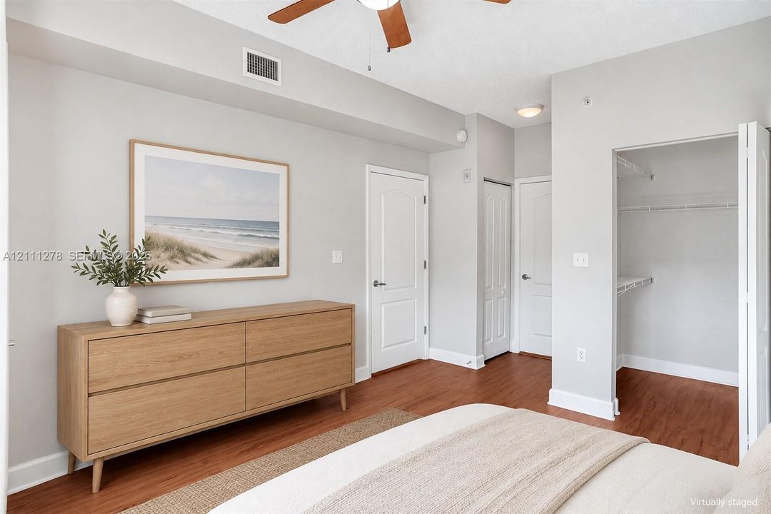 Interior room featuring wood-finish flooring, two-panel interior doors, a ceiling fan, and a built-in closet with wire shelving