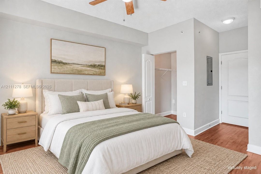 Wood-finish flooring, ceiling fan with light fixture, neutral wall color, and closet with built-in shelving