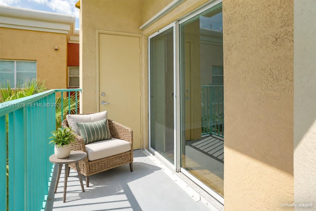 Private balcony featuring a textured stucco finish, metal railing, and a full-height glass sliding door