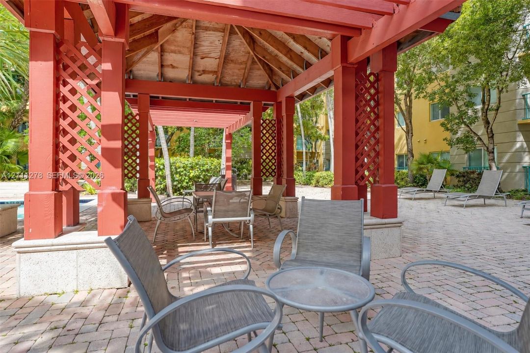 Covered pergola featuring cedar-tone support columns, decorative lattice side panels, and a concrete paver patio