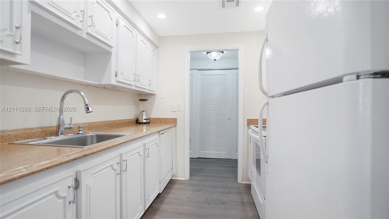 Kitchen featuring white cabinetry, stone-finish countertops, stainless steel sink with gooseneck faucet, recessed lighting, and wood-finish flooring