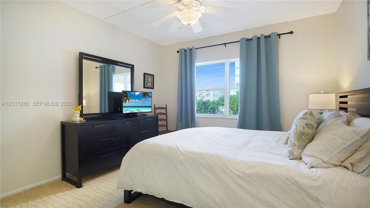 Neutral-toned room featuring a central ceiling fan with an integrated light fixture and a large rectangular window