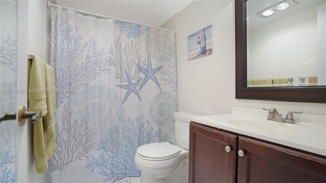 Bathroom featuring a dark wood-finish vanity, integrated sink basin with a dual-handle faucet, and a wall-mounted mirror with a matching dark wood frame