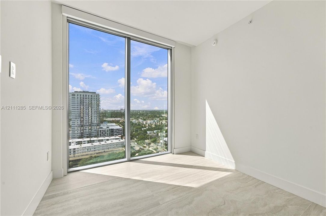 Floor-to-ceiling windows, neutral interior walls, and light-toned tile flooring