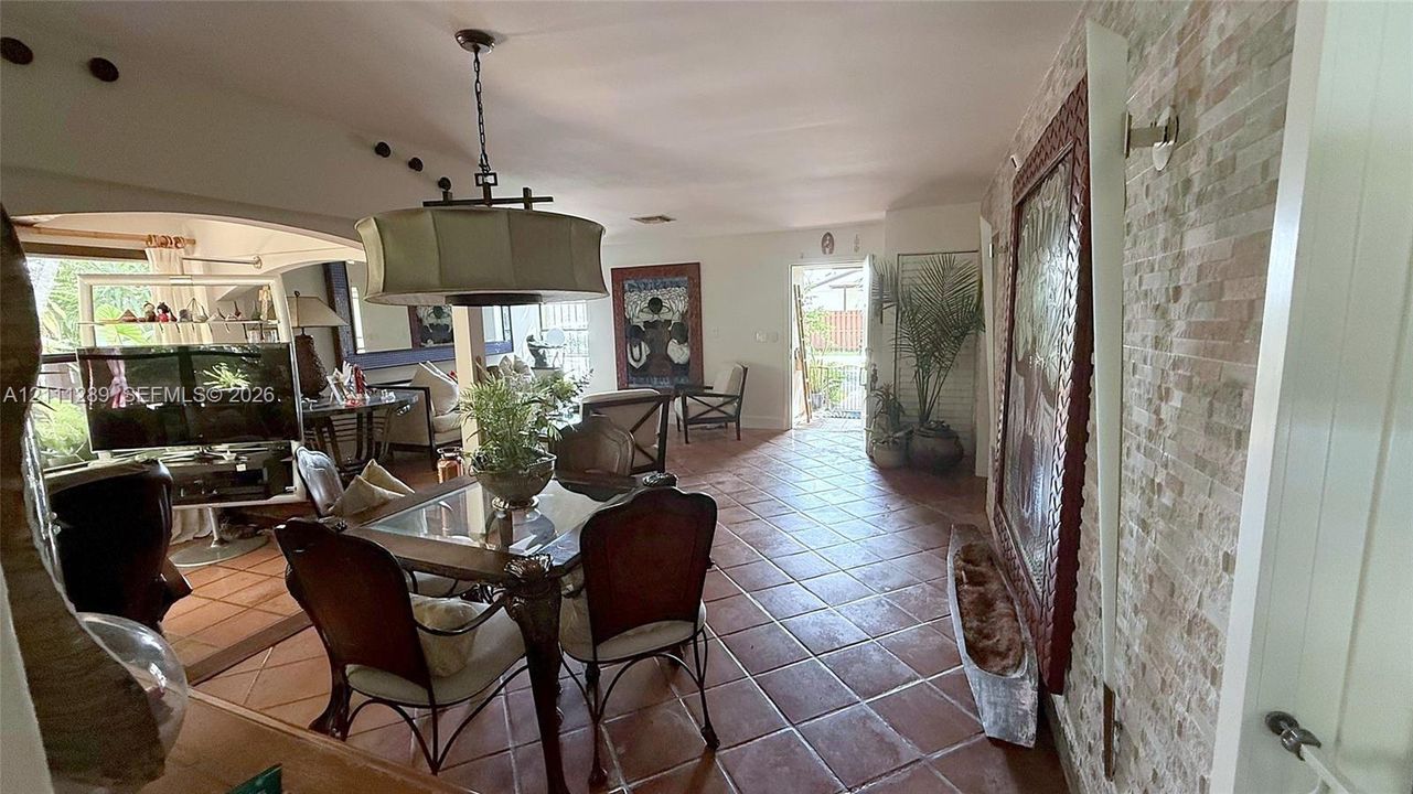 Terra cotta tile flooring, stacked stone wall accent, and a drum-style pendant light fixture