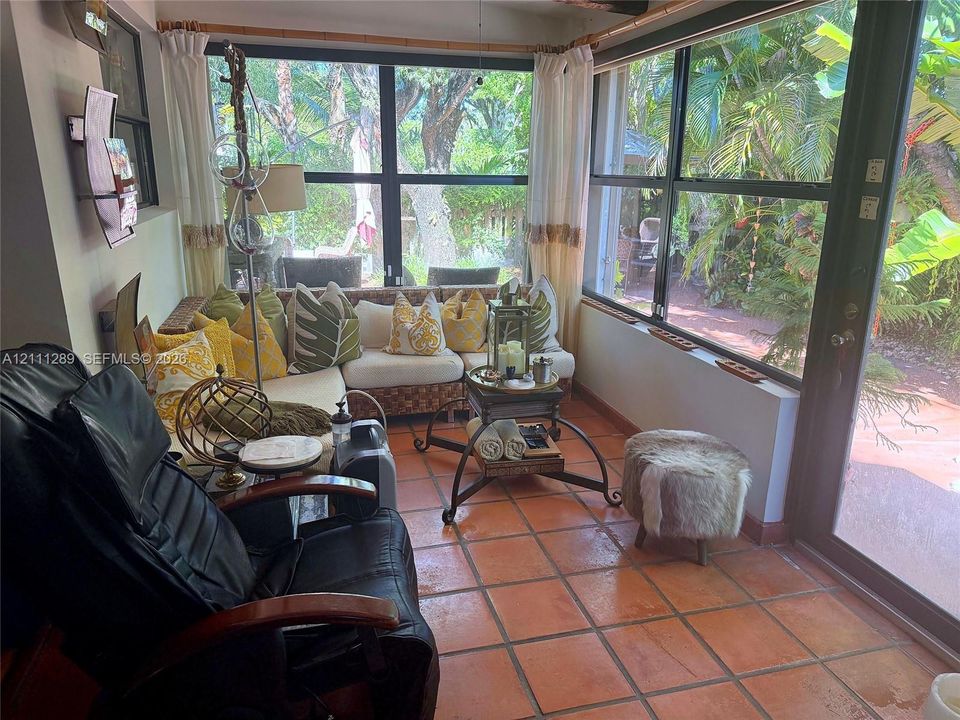 Sunroom featuring ceramic tile flooring, floor-to-ceiling windows, and a glass-paneled door