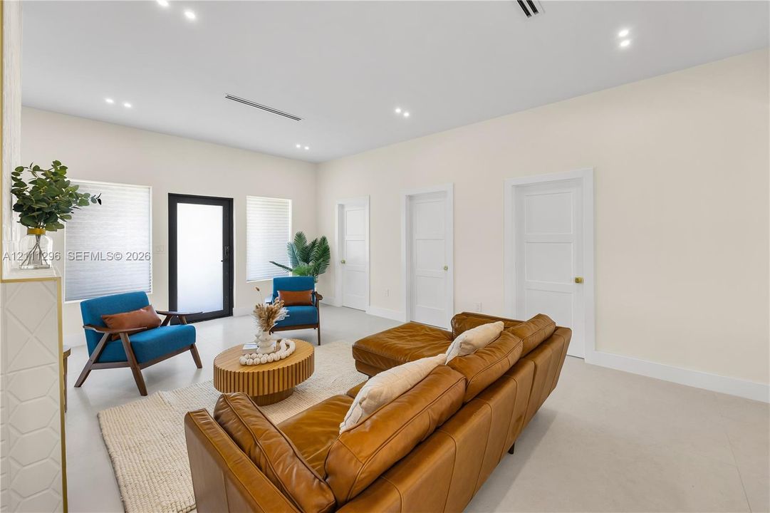 Neutral-toned interior featuring smooth-finish flooring, recessed ceiling lighting, three paneled interior doors, and a black-framed glass-panel entry door