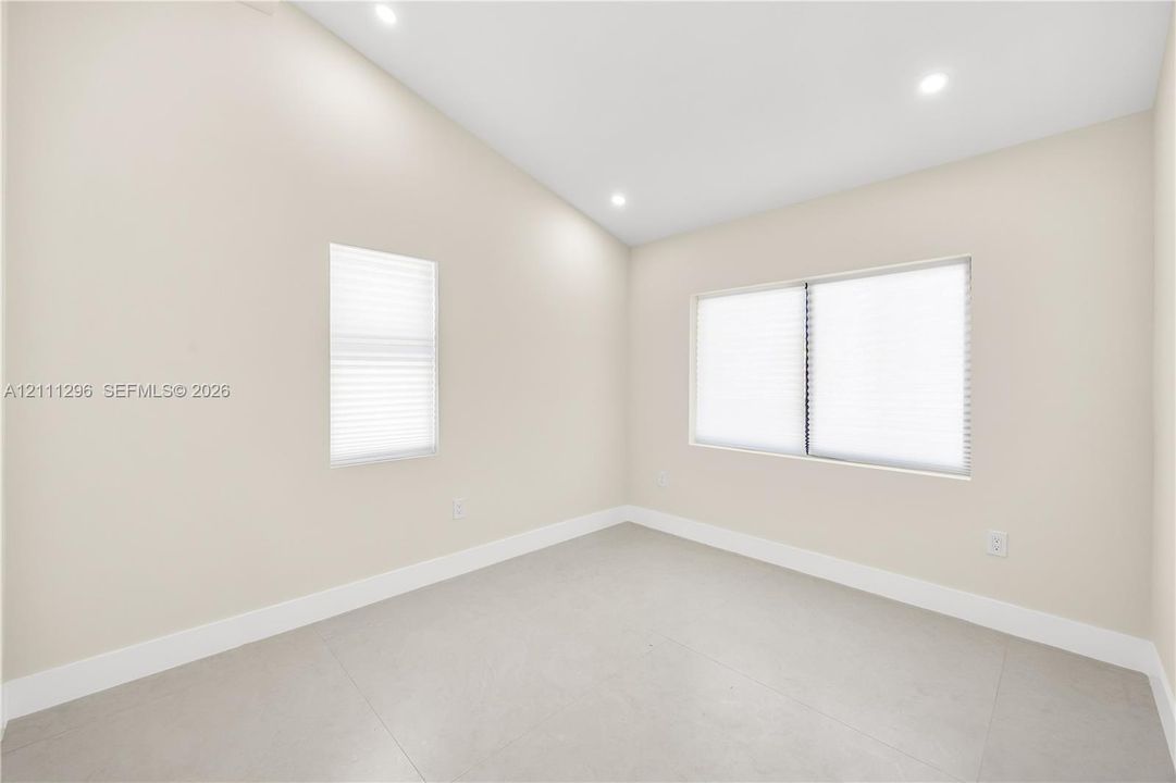 Vaulted ceilings featuring recessed lighting, large-format neutral tile flooring, and multiple windows with integrated blinds