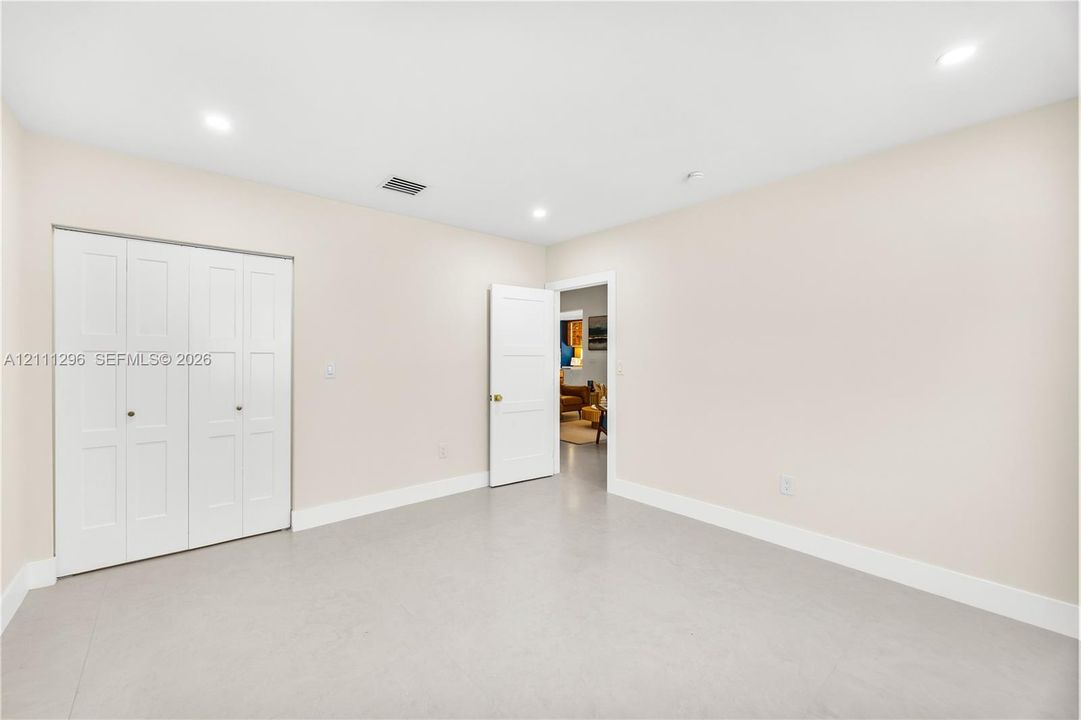 Neutral-toned interior room featuring recessed lighting, a three-panel door, and a white bi-fold closet