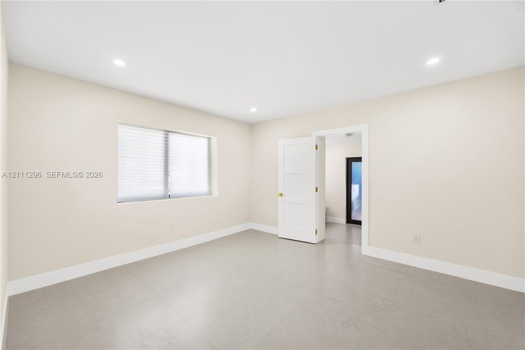 Neutral-toned tile flooring, recessed ceiling lighting, and a three-panel interior door