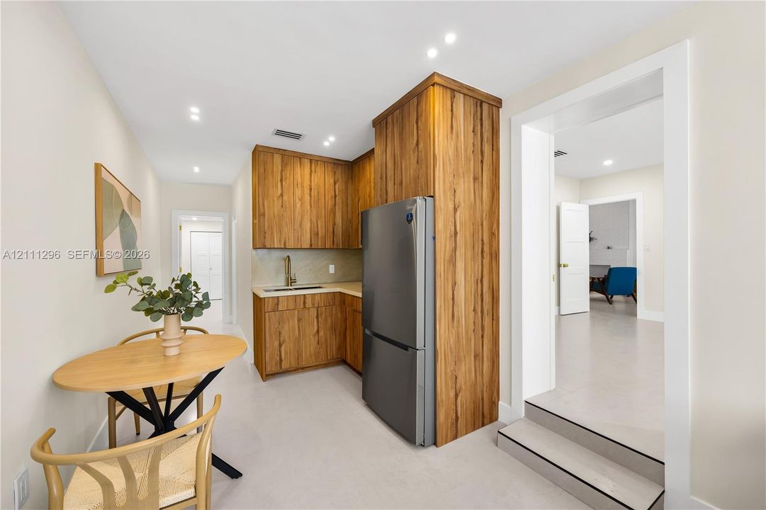 Kitchenette featuring wood-finish cabinetry, stainless steel refrigerator, stone-surface countertop, and recessed lighting