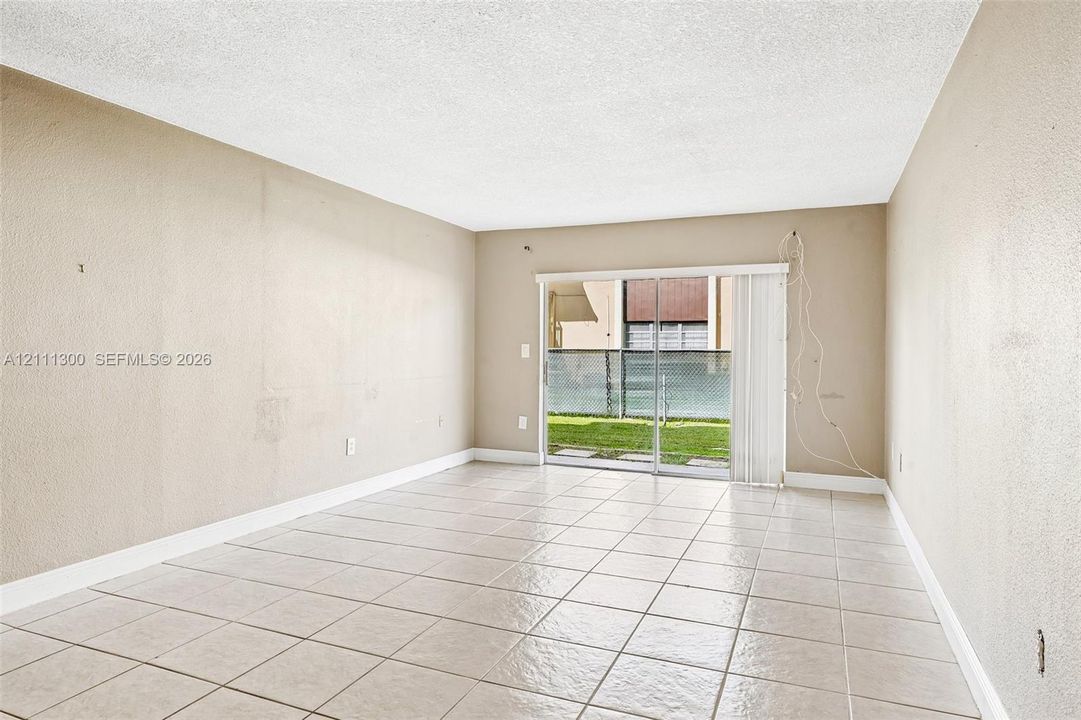 Neutral-toned interior space featuring ceramic tile flooring and sliding glass doors providing outdoor access