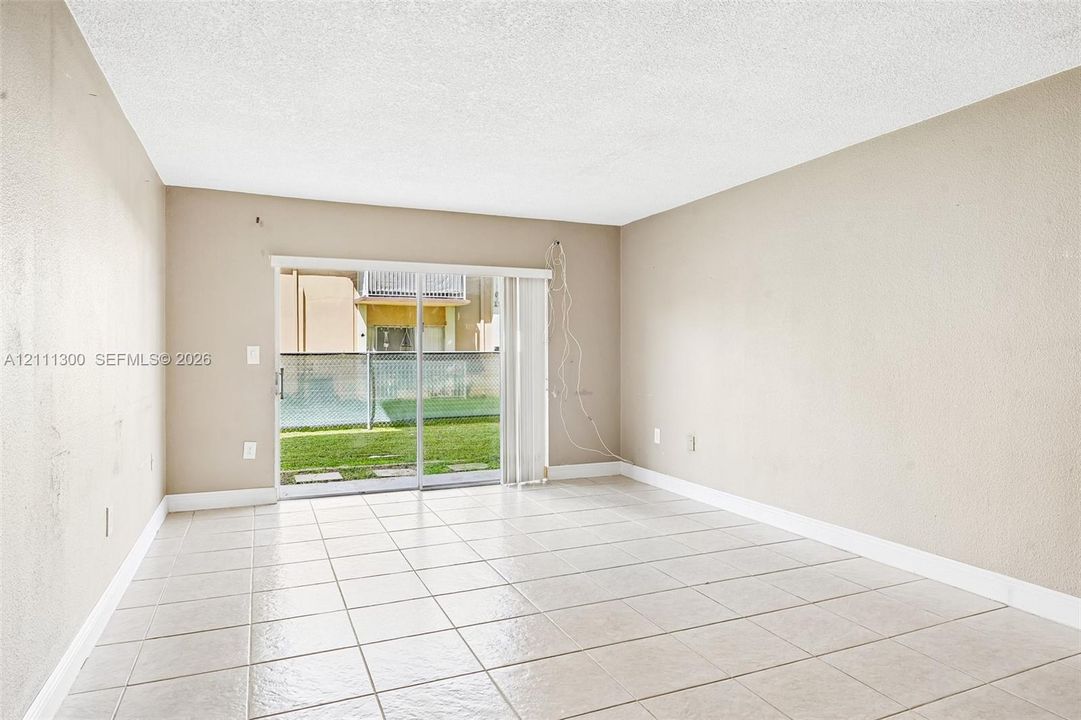 Neutral-toned interior featuring ceramic tile flooring and sliding glass doors with access to an exterior concrete patio