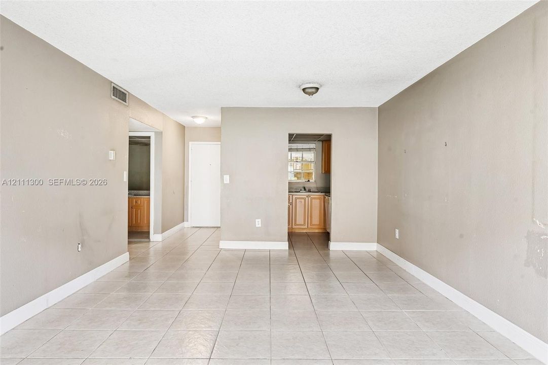 Neutral-toned interior space featuring large-format ceramic tile flooring, textured ceilings, and flush-mount lighting fixtures