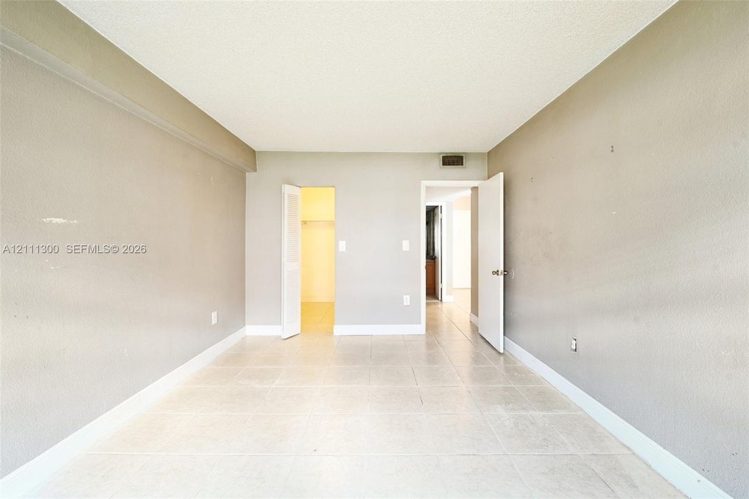Neutral-toned room featuring large-format tile flooring and a walk-in closet with built-in shelving
