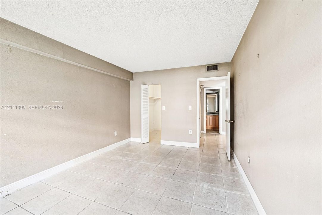 Interior space featuring neutral-tone walls, large-format tile flooring, and a walk-in closet with built-in shelving