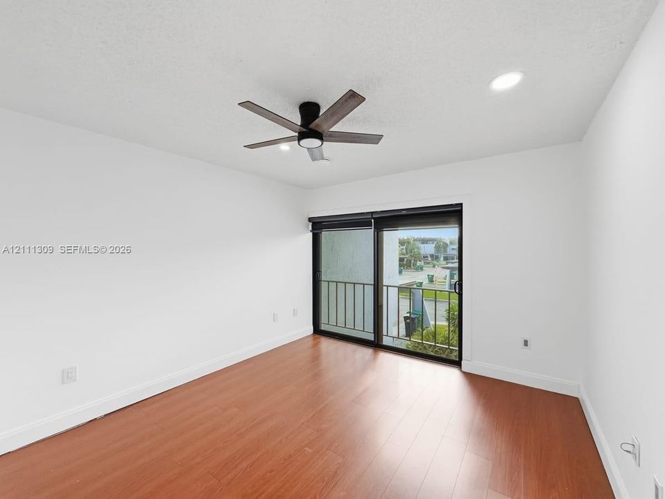 Interior space featuring wood-finish flooring, sliding glass door, recessed lighting, and a modern ceiling fan with a dark wood finish
