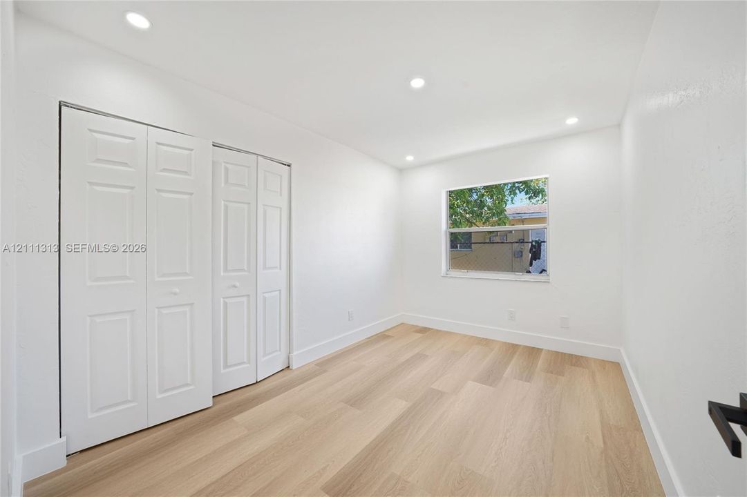 Wood-finish flooring, recessed lighting, and white panel bi-fold closet doors