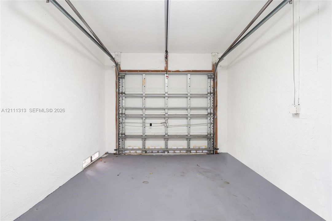Enclosed garage space featuring painted walls, overhead door tracks, and a finished floor surface