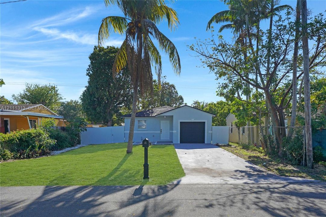 Single-story exterior featuring a concrete driveway, attached one-car garage, manicured lawn, and perimeter privacy fencing