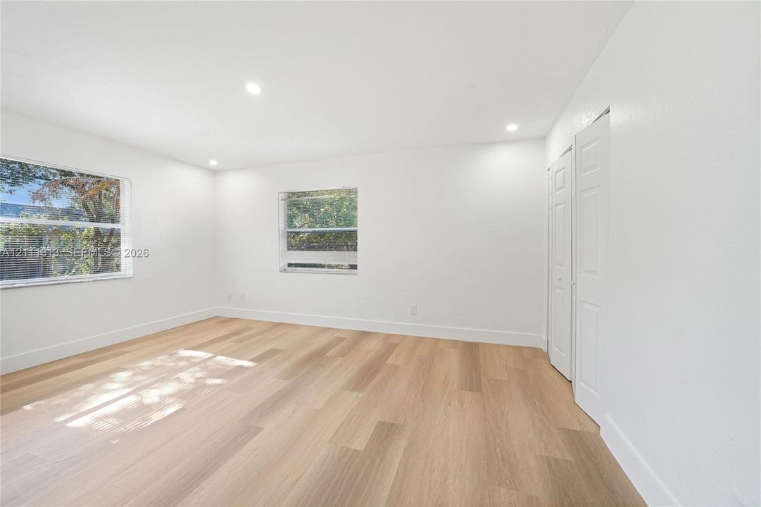 Neutral interior space featuring wood-finish flooring, recessed lighting, and dual-panel closet doors