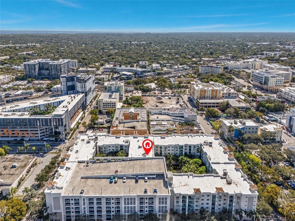 Aerial perspective of a multi-story residential complex featuring an integrated multi-level parking structure and a central courtyard with established palm trees