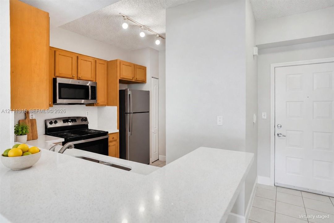 Kitchen featuring stone-finish countertops, stainless steel appliances, wood cabinetry, and track lighting