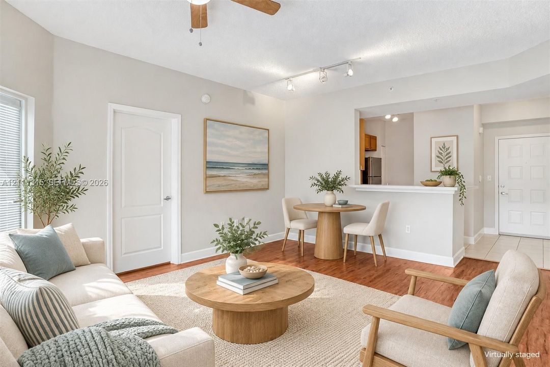 Open-concept interior featuring wood-finish flooring, a ceiling fan, track lighting, and a passthrough kitchen window with a ledge