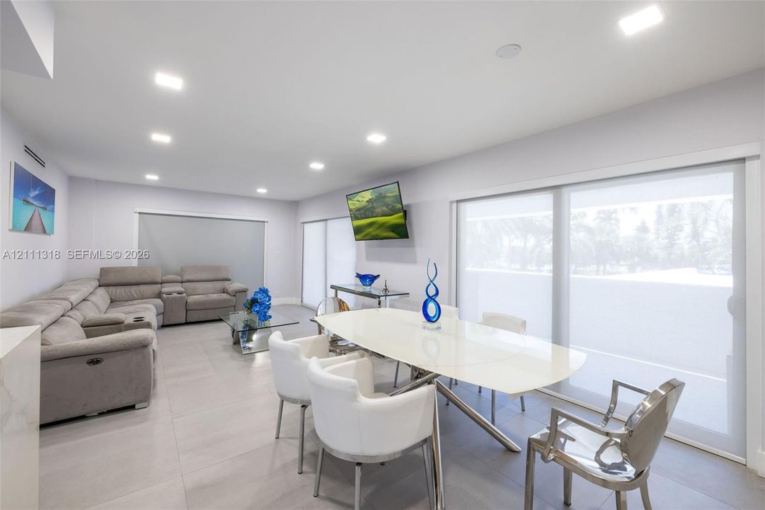 Neutral-toned interior space featuring oversized ceramic tile flooring, recessed LED lighting, and expansive floor-to-ceiling sliding glass doors